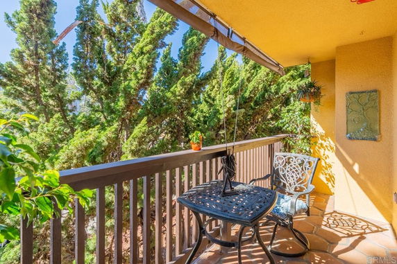 Balcony view with patio furniture and trees in the background.