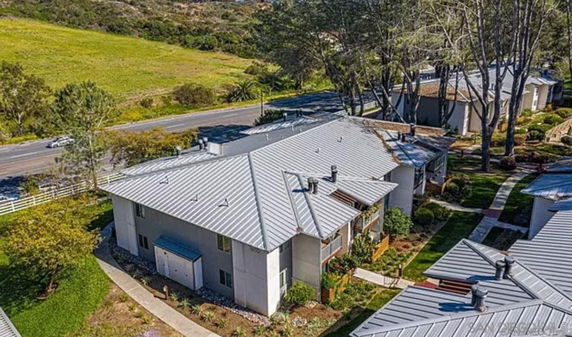 Aerial view of a row of houses with metal roofs and surrounding greenery.