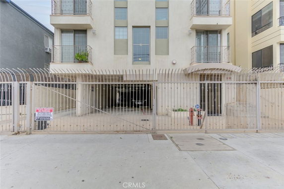 Front view of a multi-story building with balconies and gated entrance.