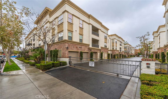 Front view of a multi-story apartment building with secured gate entrance.