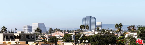 Wide-angle view of a cityscape with multiple buildings and palm trees.