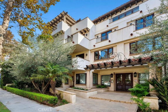 Front view of a multi-story residential building with balconies and a decorative entrance.