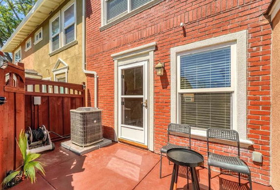 Rear view of a house with a brick exterior and a small patio area.