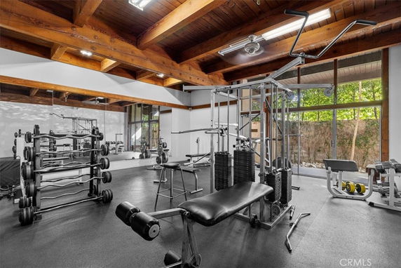 Indoor gym area with fitness equipment and wooden ceiling beams.