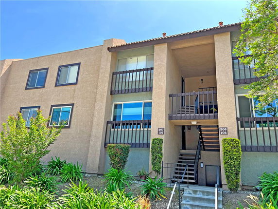 Front view of a multi-story residential building with balconies and stairway.