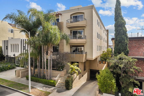 Front view of a multi-story residential building with balconies and an entrance gate.