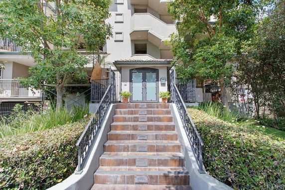 Front view of a multi-story building with stairs leading to the entrance.