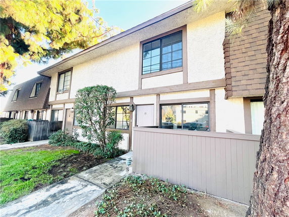 Front view of a two-story townhouse with brown trim and a small fenced front area.