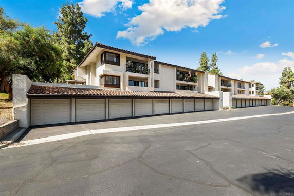 Front view of a multi-story residential building with a row of garage doors on the ground level.