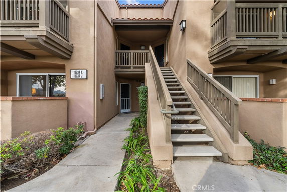 Front view of a multi-story building with an exterior staircase and balconies.