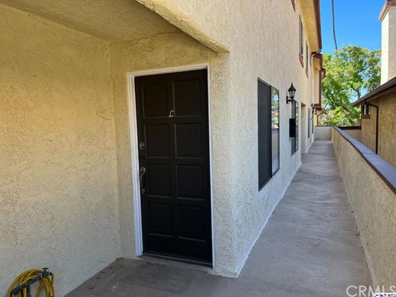 Front entrance view of a residential building with a black door and stucco exterior.