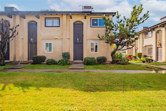 Front view of a two-story building with distinct arched doorways and a small garden.