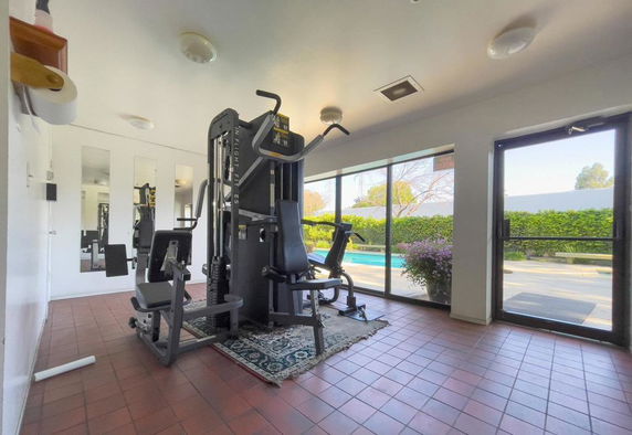 Indoor gym area with exercise equipment and tile flooring.