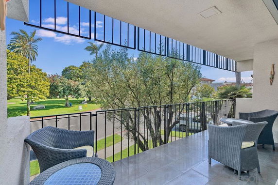 Balcony with outdoor seating overlooking a garden and trees.