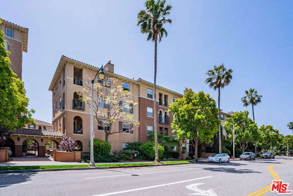 Front view of a multi-story residential building with balconies and arched windows.