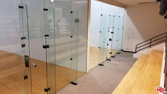 Indoor squash court with glass walls and wooden flooring