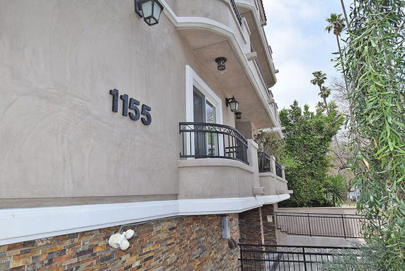 Front view of a multi-story building with balconies and stone veneer accents.