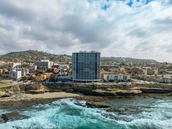 View of a coastal cityscape with a prominent tall building near the shoreline.