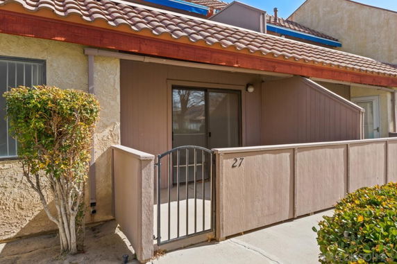 Front view of a single-story house with a small gated patio and tiled roof.