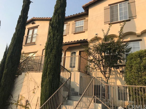 Front view of a two-story house with stucco exterior and multiple windows.