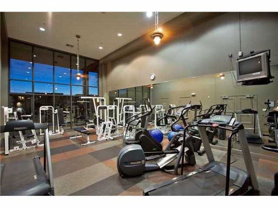 Indoor gym area with various exercise equipment and large mirrors.