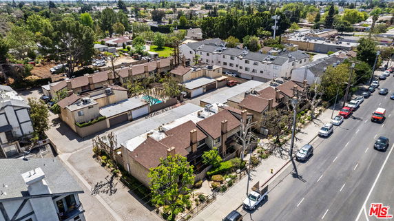 Aerial view of a residential area with multiple townhouses and surrounding greenery.