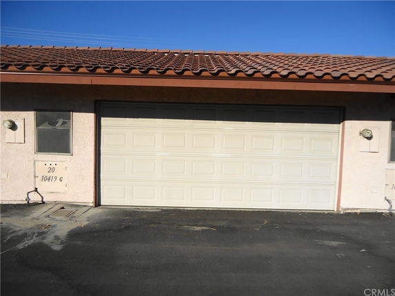 Front view of a building with a garage door and tiled roof.