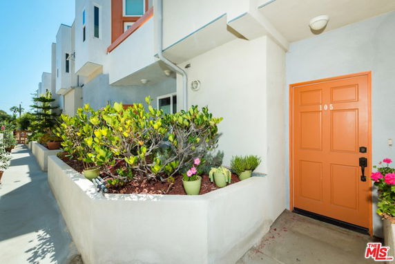 Front view of a house with an orange door and a small garden area.