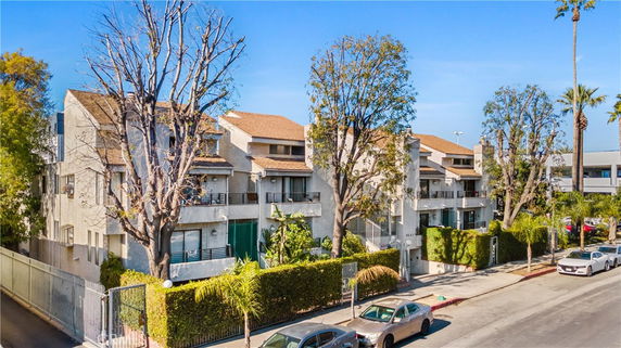 Front view of a multi-story residential building with balconies and trees.