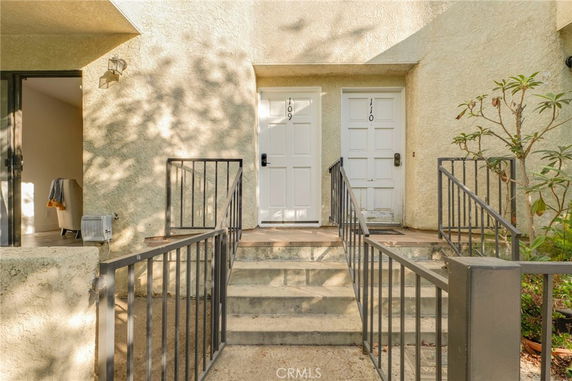 Front view of a building entrance with two white doors labeled 109 and 110, and metal railings.