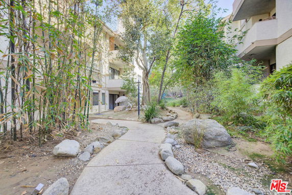 Front view of a multi-story building with a curved pathway and landscaped garden.
