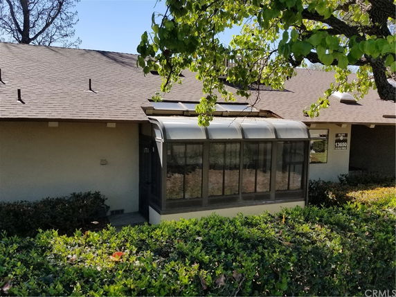 Front view of a house with a sunroom and a shingled roof.