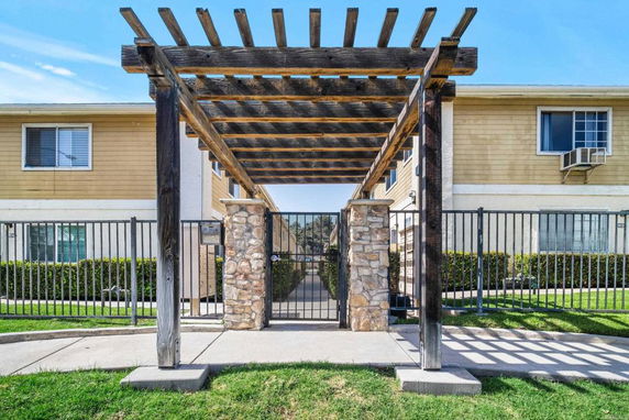 Front view of a residential building with a stone and wood pergola entrance.