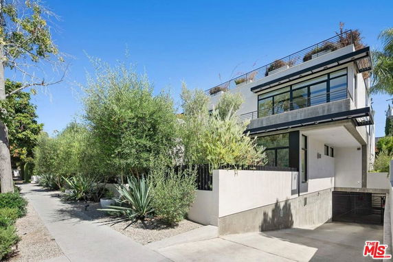 Front view of a modern two-story house with large windows and a driveway.