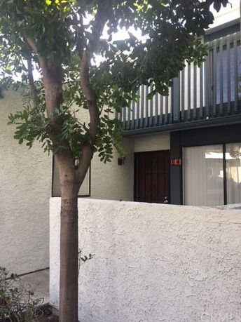 Front view of a two-story building with balcony and a small courtyard.
