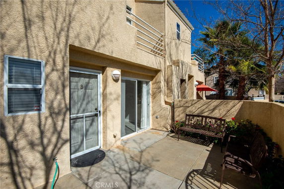 Front view of a multi-story house with a small patio and entrance door.
