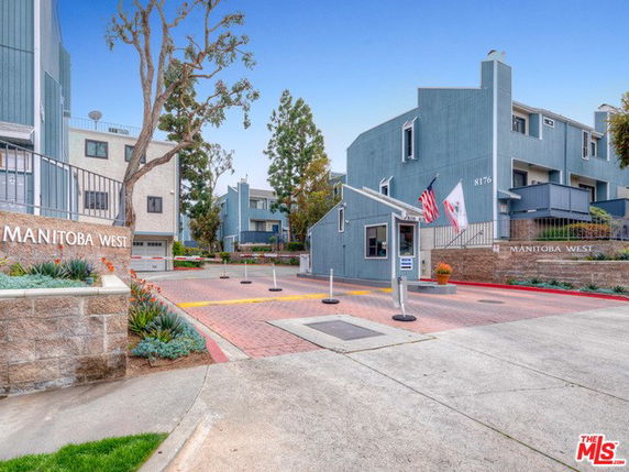 Front view of a residential complex with a security gate and modern architecture.