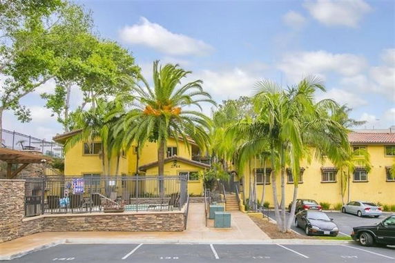 Front view of a two-story building with yellow exterior and palm trees.