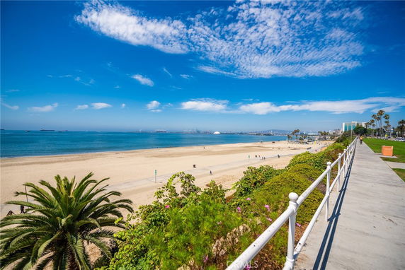 Panoramic view of a sandy beach with a clear blue sky and ocean.