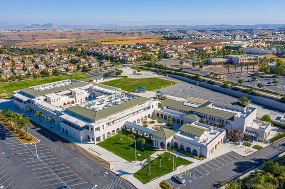 Aerial view of a large building complex with nearby residential area and parking lots.