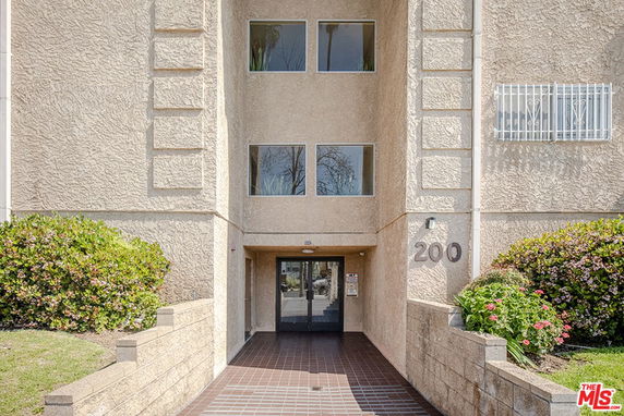 Front view of a multi-story building entrance with stucco exterior.
