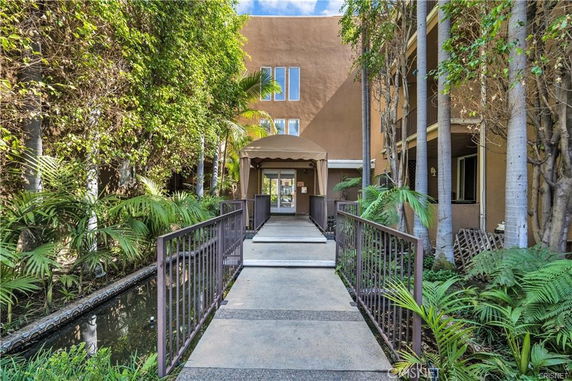 Front view of a building entrance with a pathway surrounded by greenery.