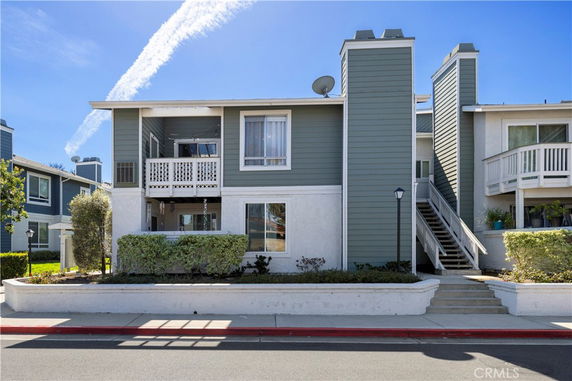 Front view of a two-story residential building with green and white exterior, balcony, and chimney.