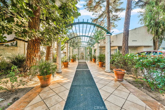 Front view of a building entrance with a tiled walkway and decorative arch.