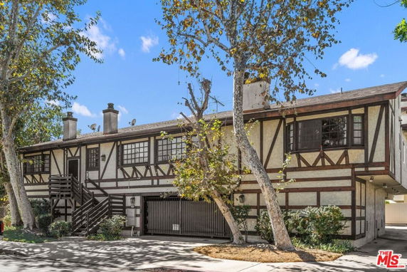 Front view of a two-story house with a wooden exterior and staircase.