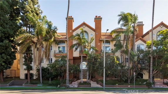 Front view of a multi-story building with a red tile roof and multiple chimneys.
