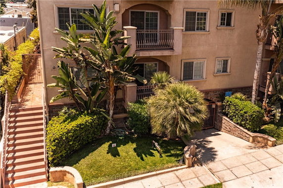 Front view of a multi-story building with balconies and surrounding greenery.