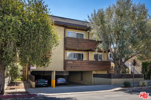 Front view of a two-story building with balconies and parking area underneath.
