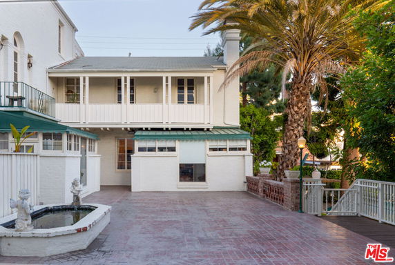 Front view of a two-story house with a balcony and a decorative driveway.