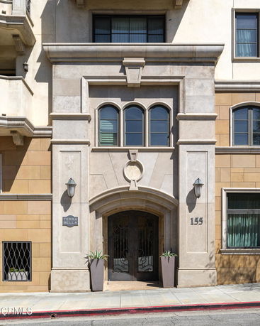 Front view of a multi-story building entrance with ornate door and decorative elements.